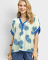 Woman wearing a blue and white patterned top on a plain background