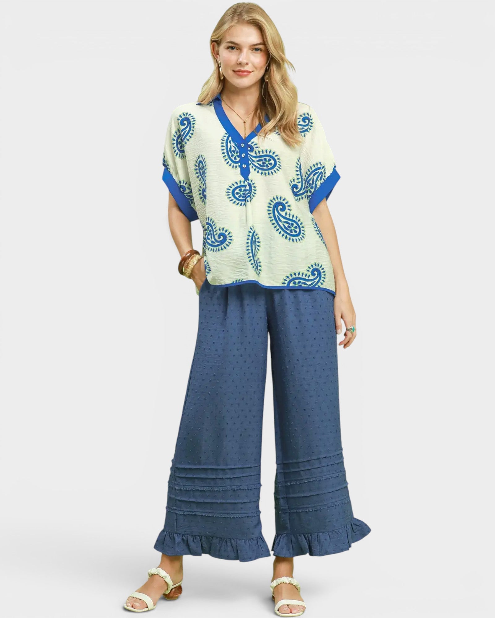 Woman wearing a patterned top and blue pants on a white background