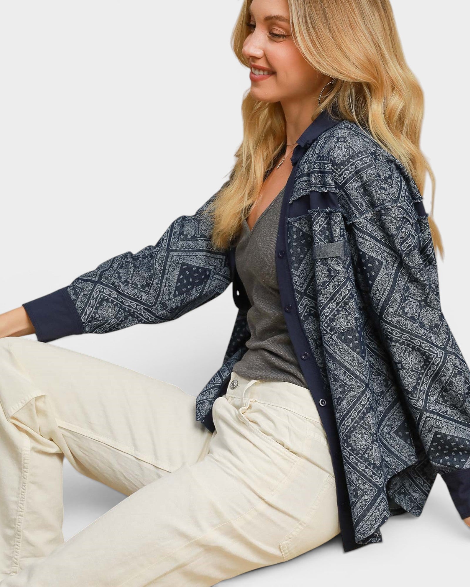 Woman wearing a patterned cardigan over a plain shirt and pants on a white background
