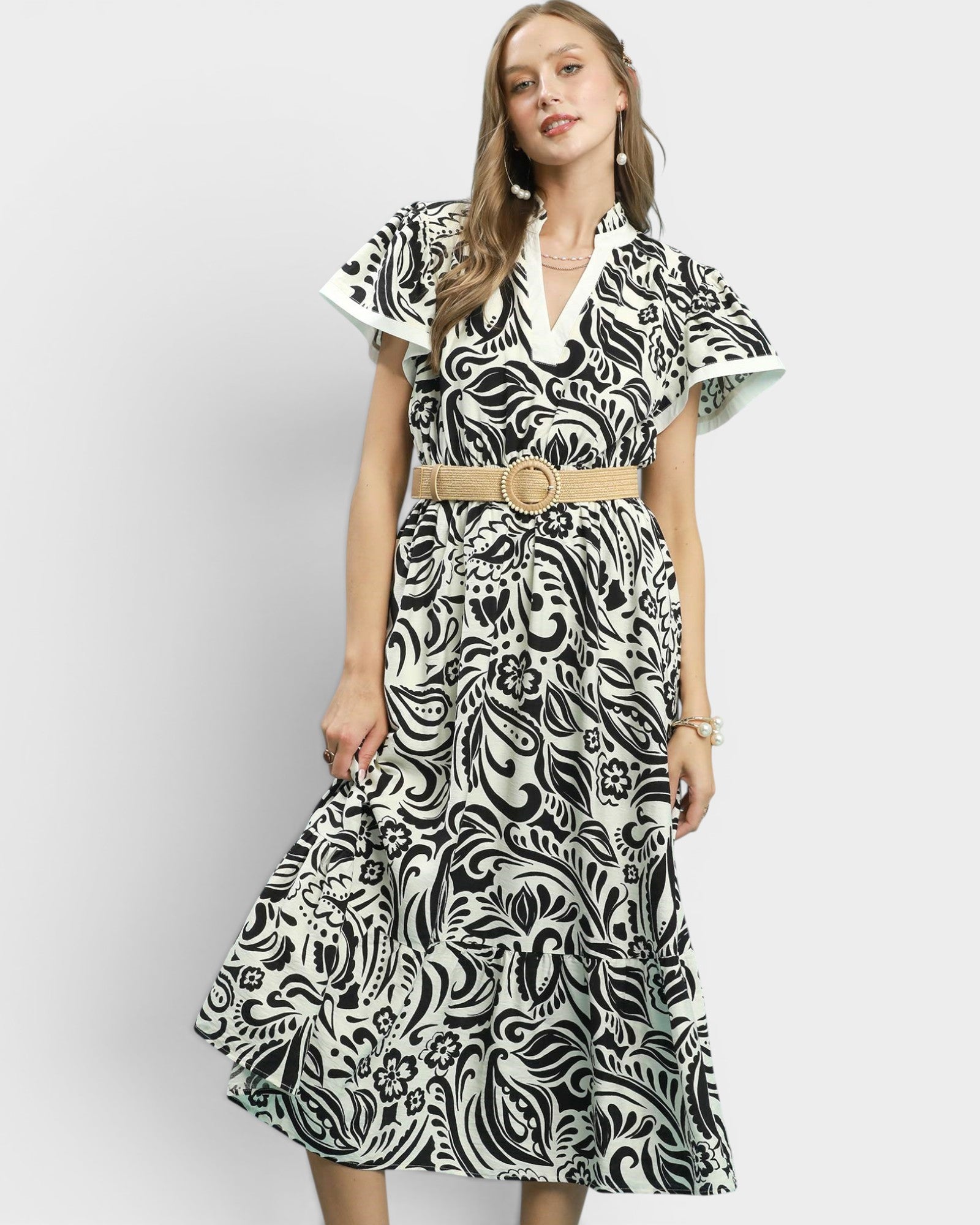 Woman wearing a black and white patterned dress with a belt on a white background