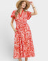 Woman wearing a red and white patterned dress with a straw hat on a white background