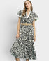 Woman wearing a black and white patterned dress with a belt on a white background