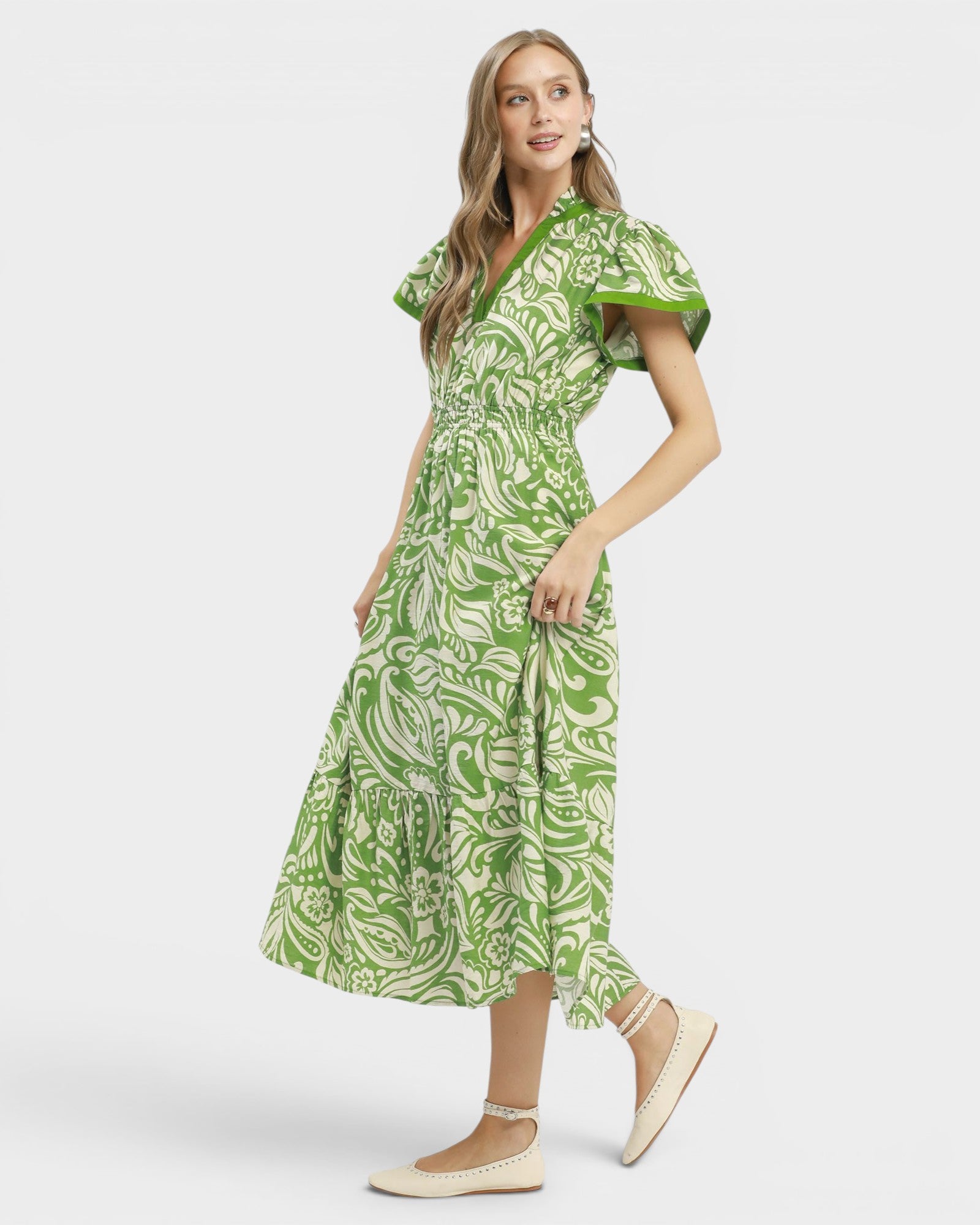Woman wearing a green patterned dress on a white background
