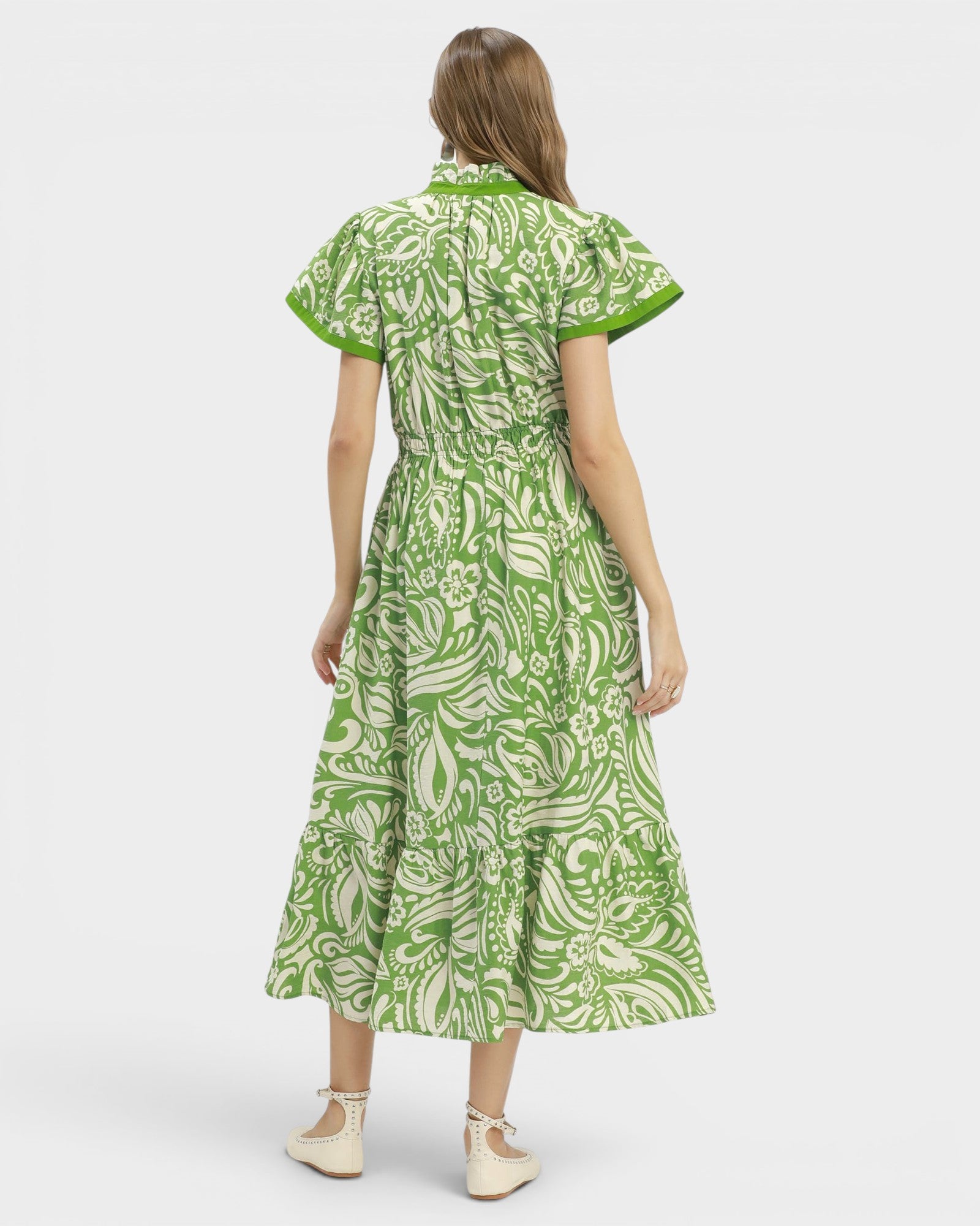 Woman wearing a green and white patterned dress on a white background