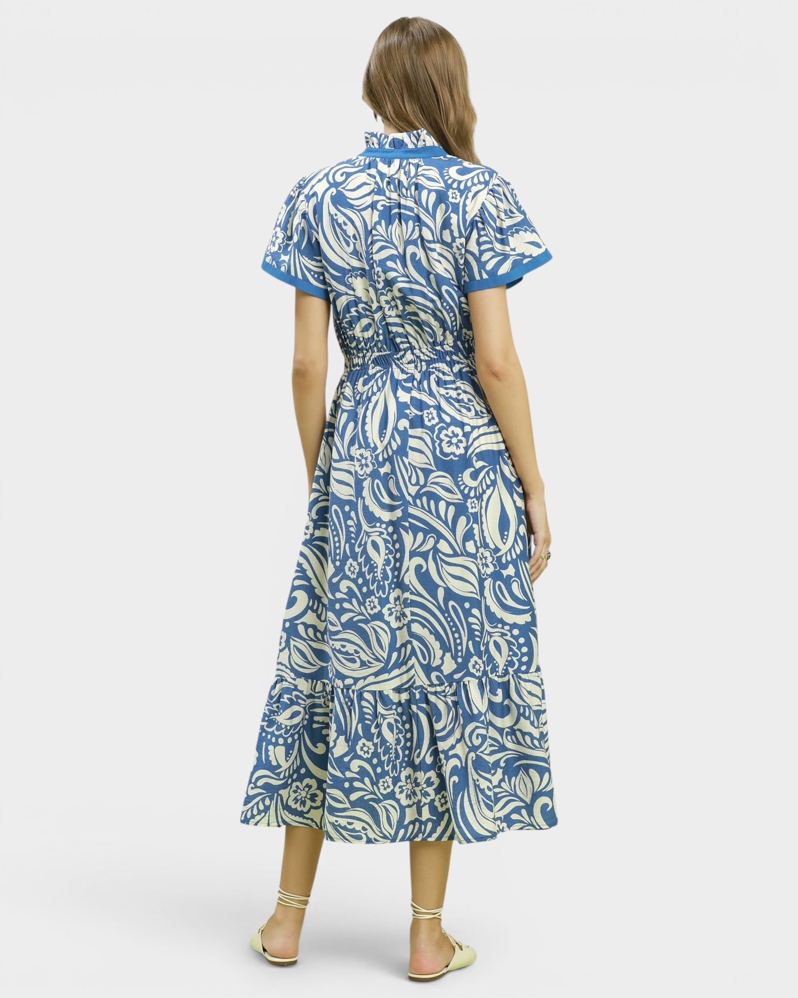 Woman wearing a blue and white patterned dress on a white background