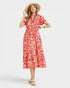 Woman wearing a red and white patterned dress with a straw hat on a white background