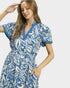 Woman wearing a blue and white patterned dress on a plain background