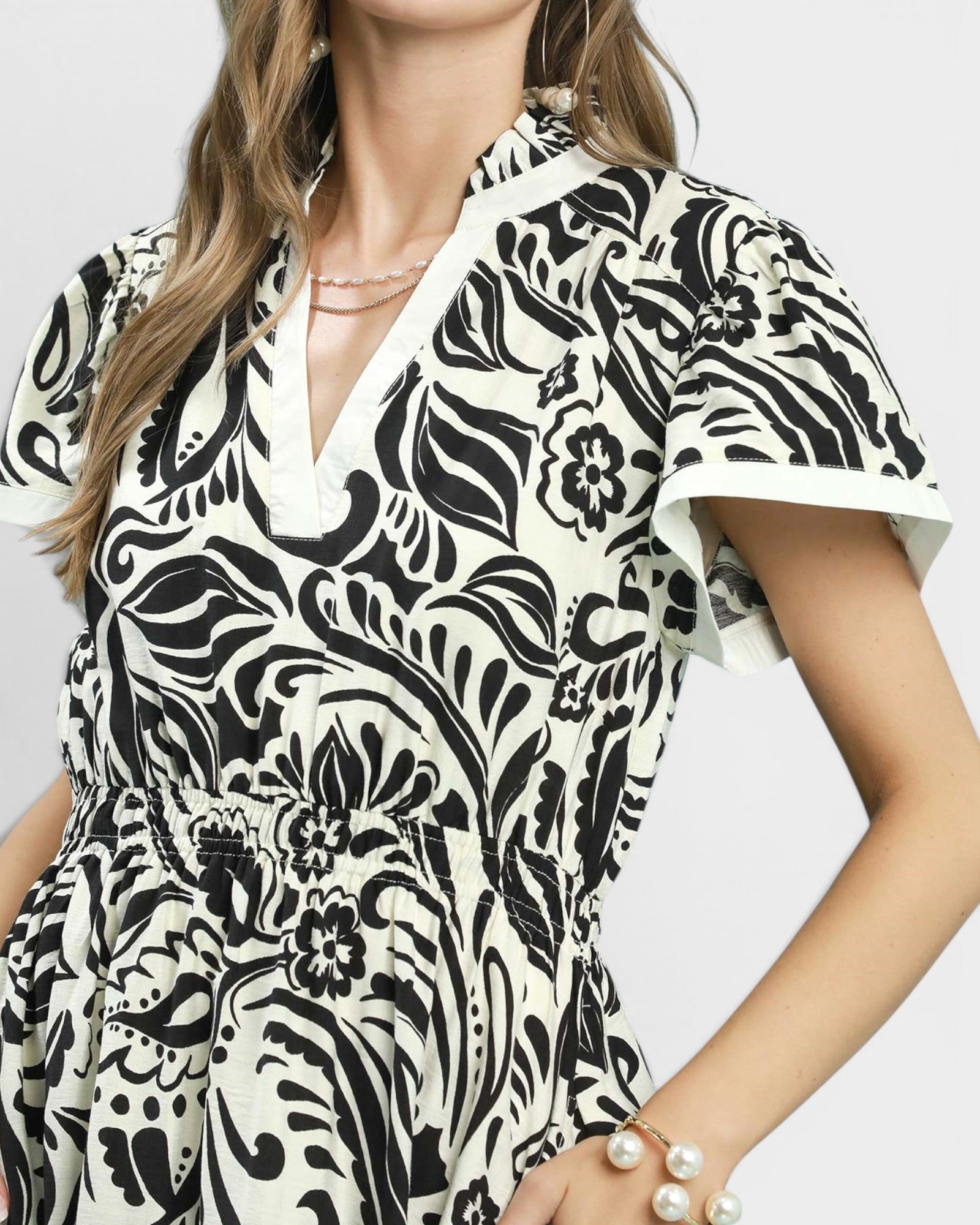 Woman wearing a black and white patterned dress on a plain background