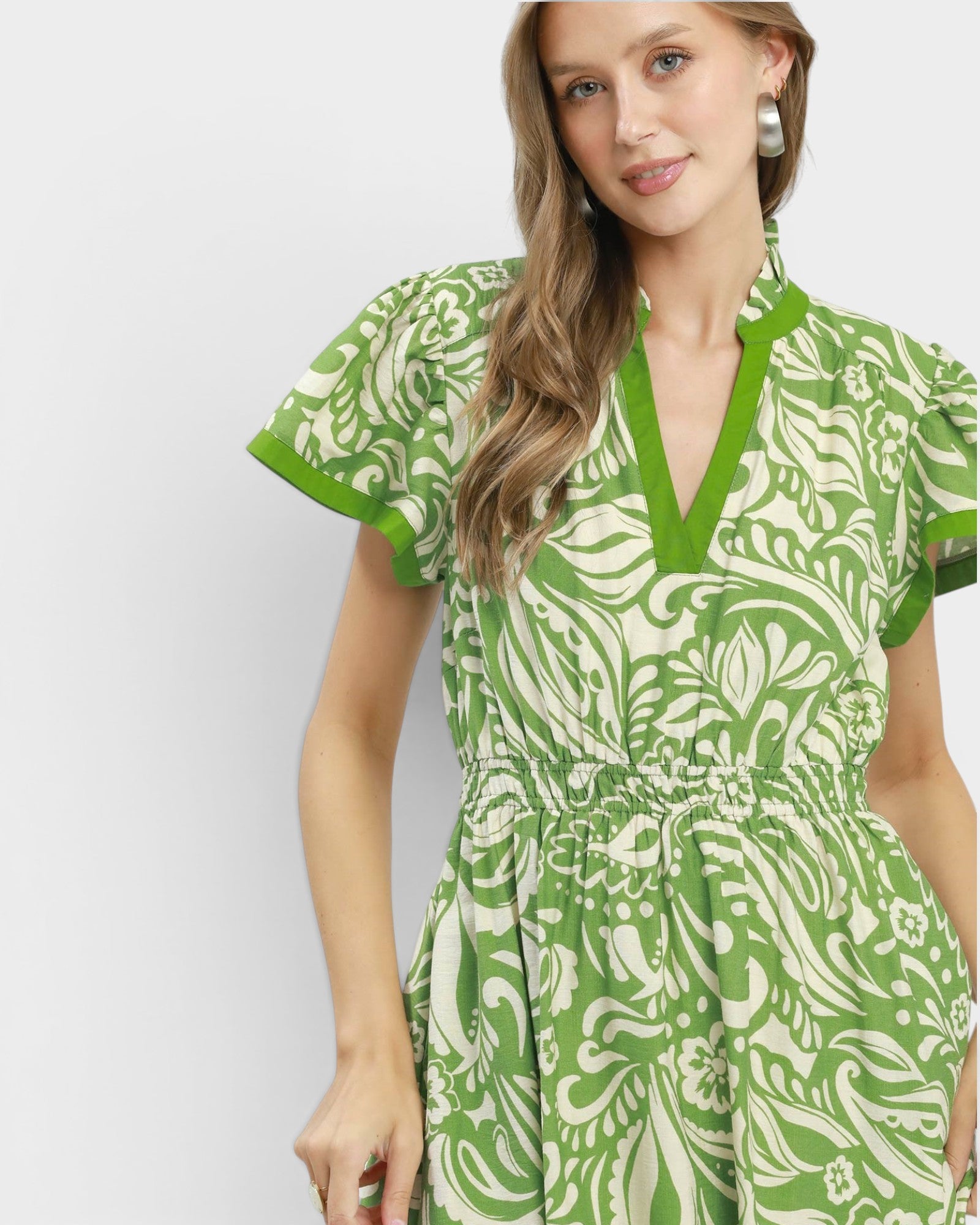 Woman wearing a green and white patterned dress on a light gray background