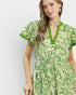 Woman wearing a green and white patterned dress on a light gray background