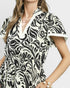 Woman wearing a black and white patterned dress on a plain background