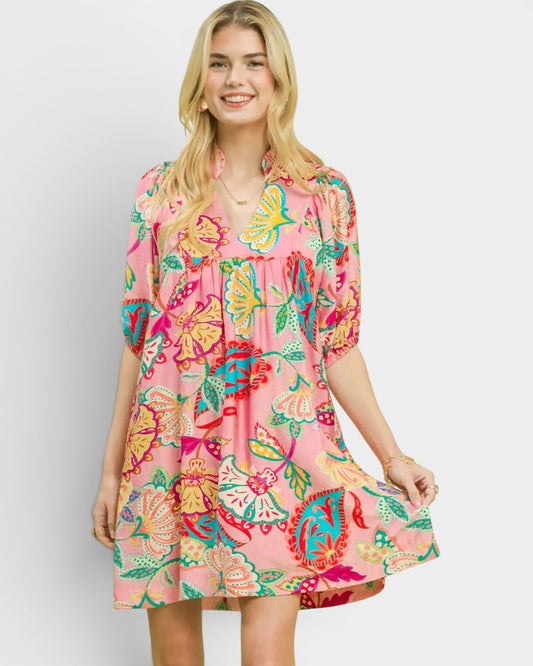 Woman wearing a colorful floral dress on a plain background