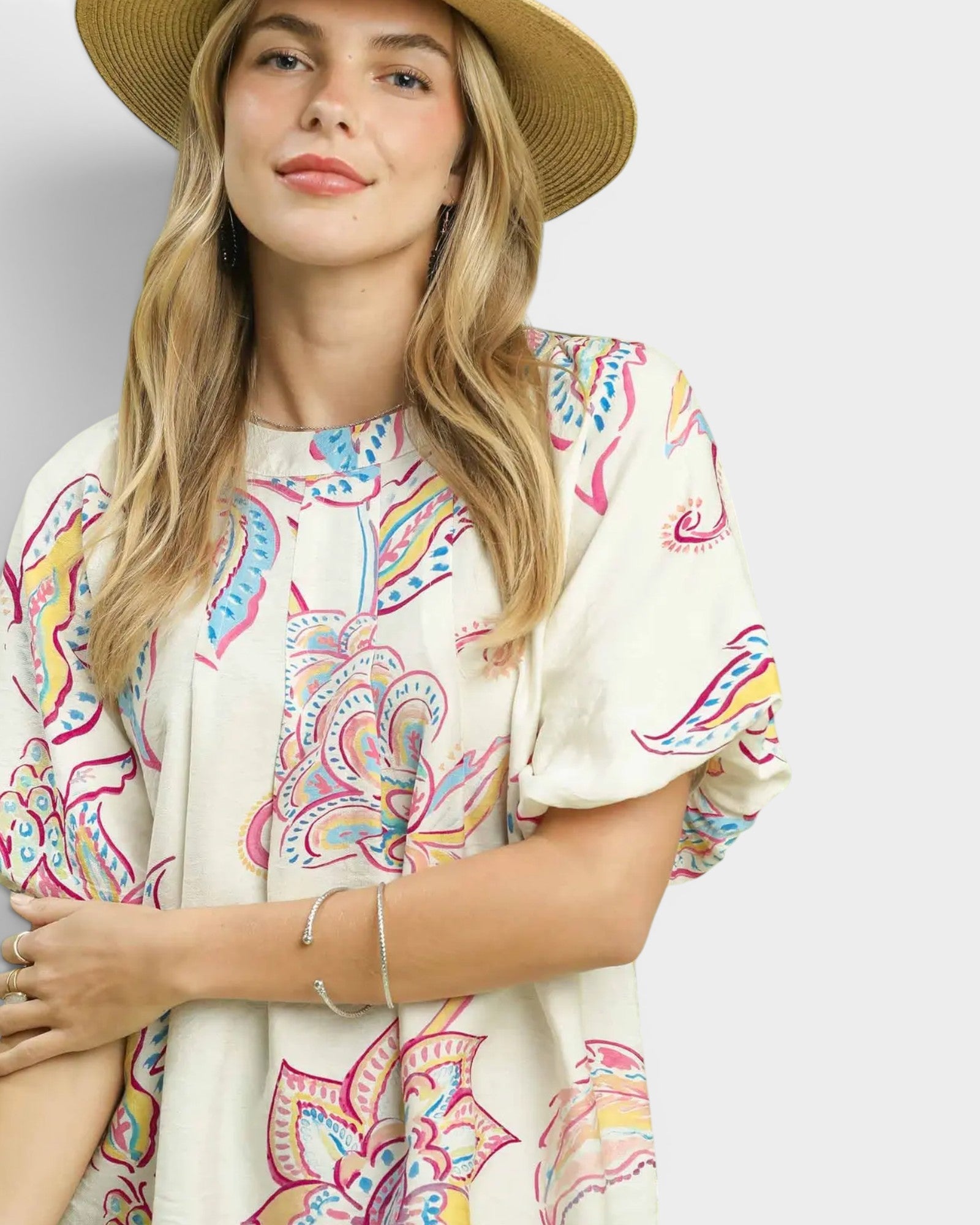 Woman wearing a colorful patterned dress and straw hat on a plain background
