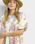 Woman wearing a colorful patterned dress and straw hat on a plain background