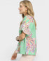 Woman wearing a green patterned blouse on a white background