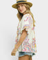 Woman wearing a colorful patterned top and straw hat on a white background