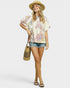 Woman wearing a colorful floral blouse, denim shorts, and a straw hat on a white background