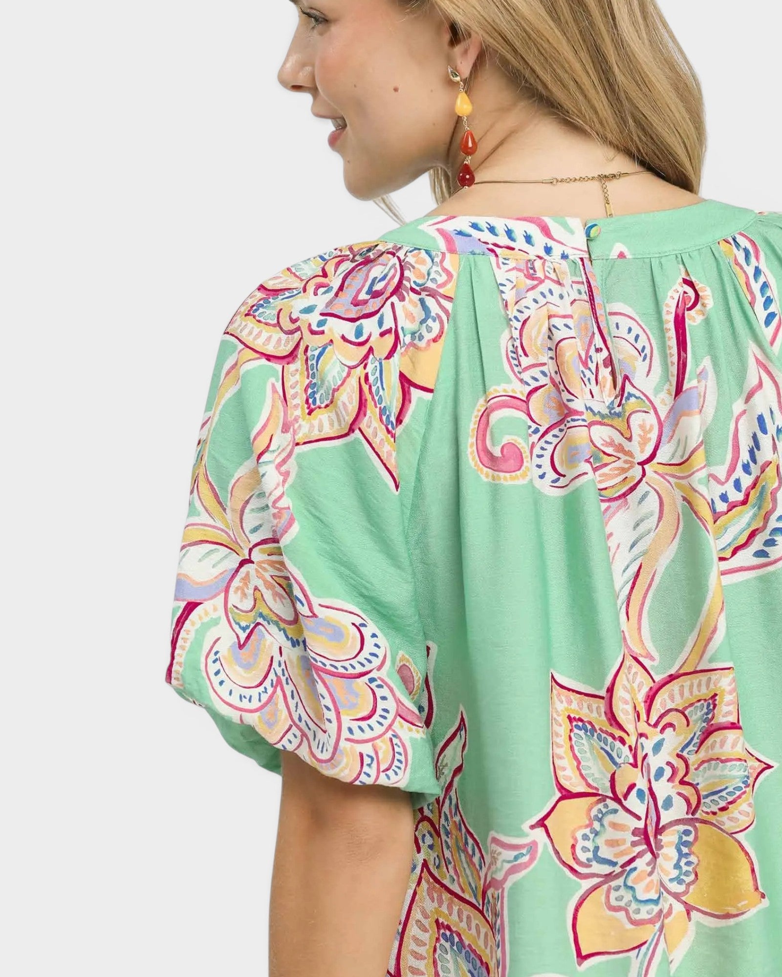 Woman wearing a green blouse with colorful floral patterns on a white background