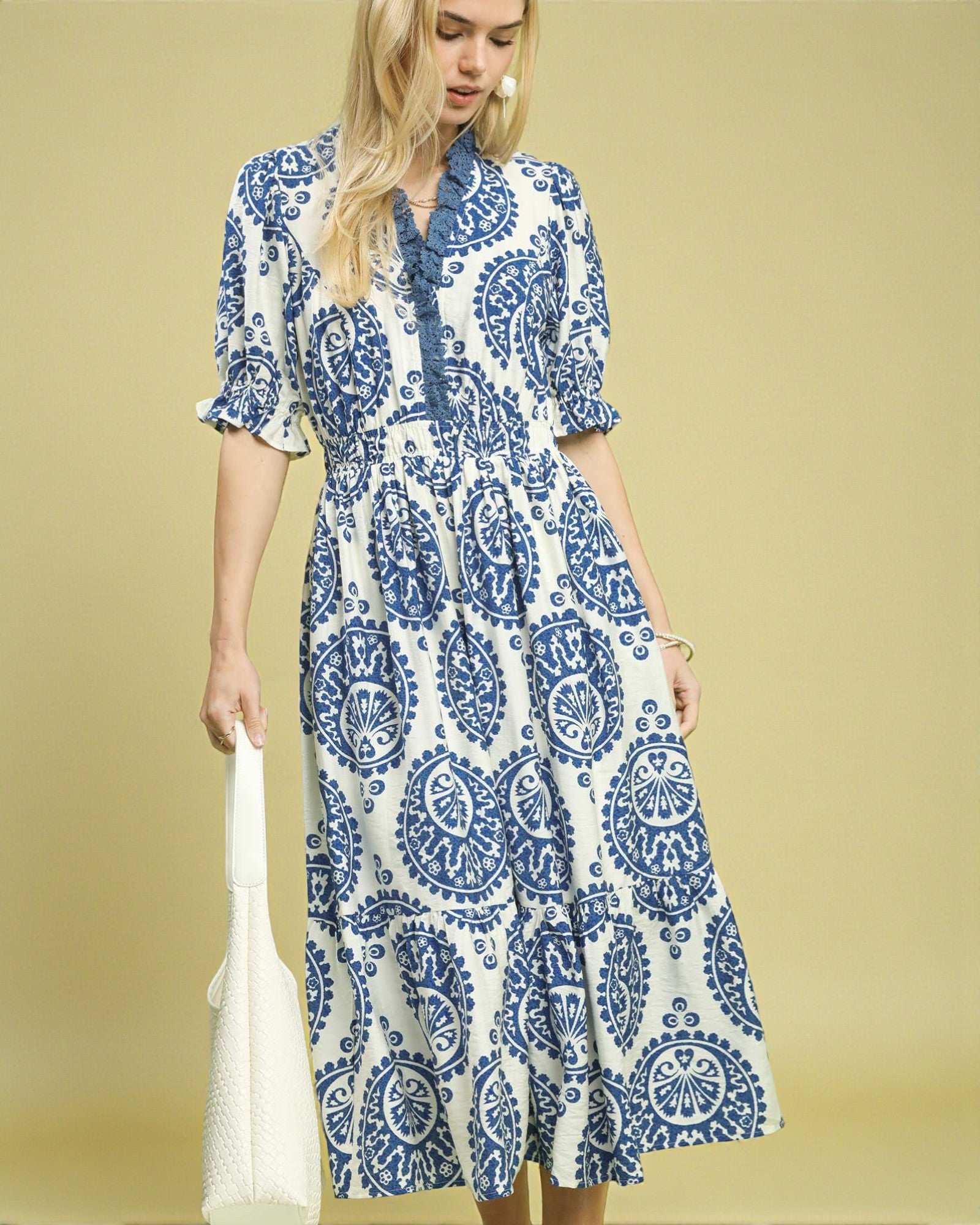 Woman wearing a blue and white patterned dress against a beige background