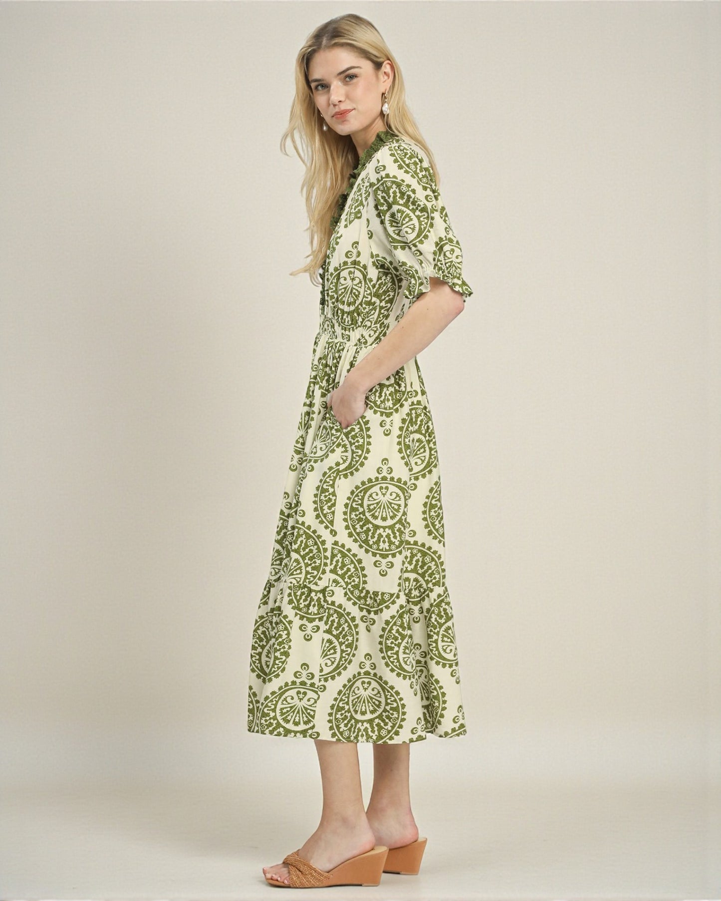 Woman wearing a green and white patterned dress on a plain background