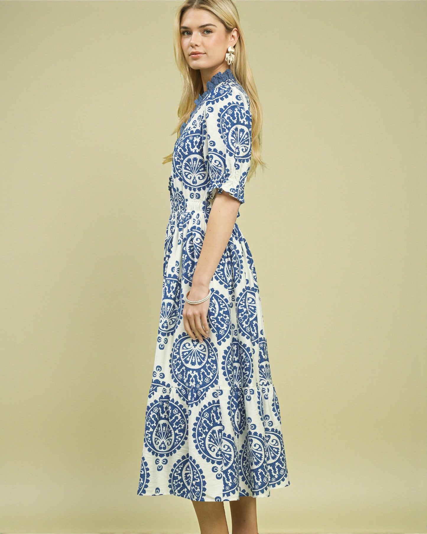 Woman wearing a blue and white patterned dress on a beige background