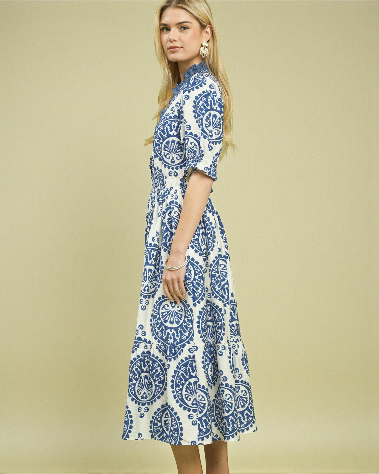 Woman wearing a blue and white patterned dress on a beige background