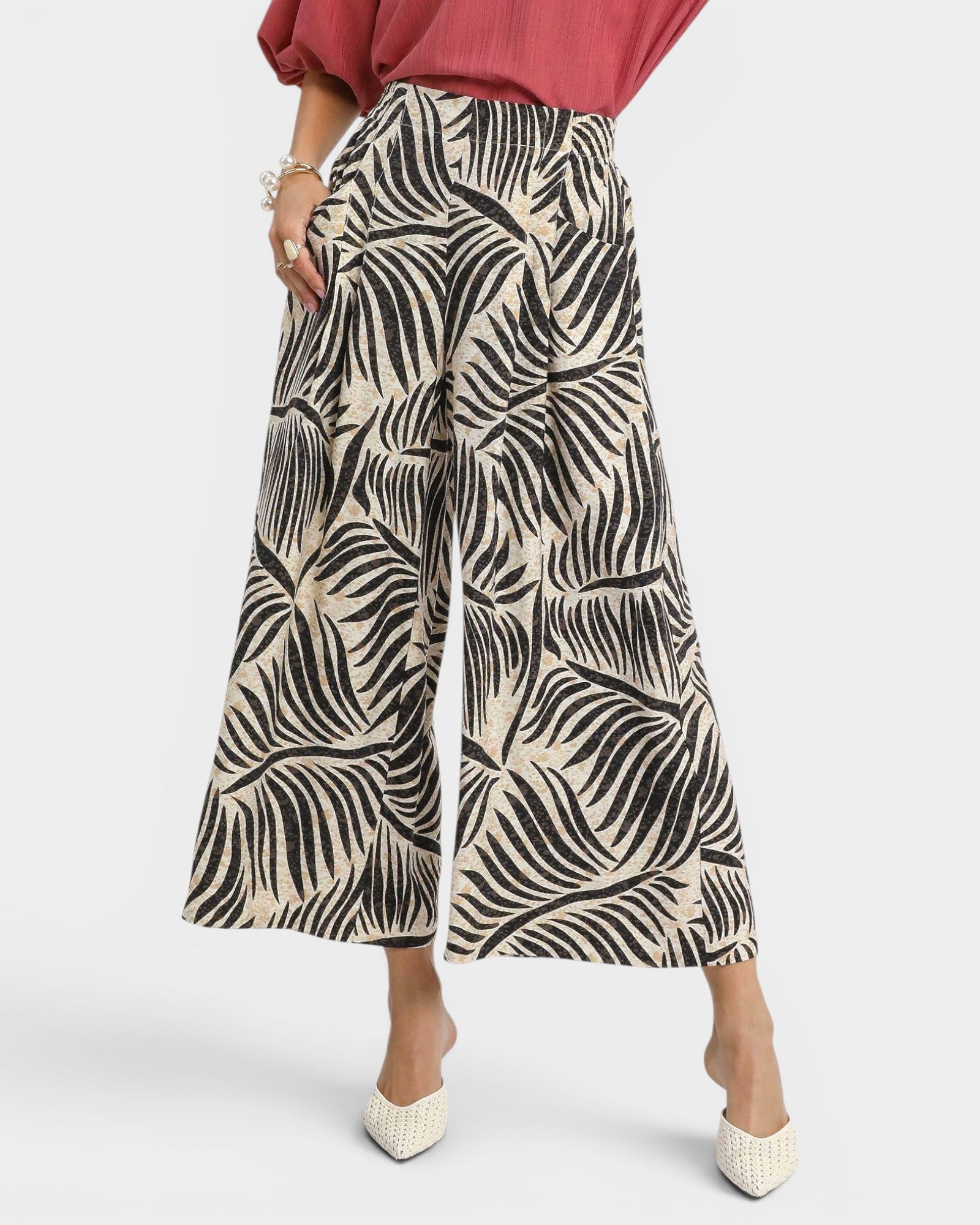 Person wearing wide-leg pants with a leaf pattern on a white background
