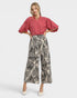 Woman wearing a pink blouse and patterned pants on a white background