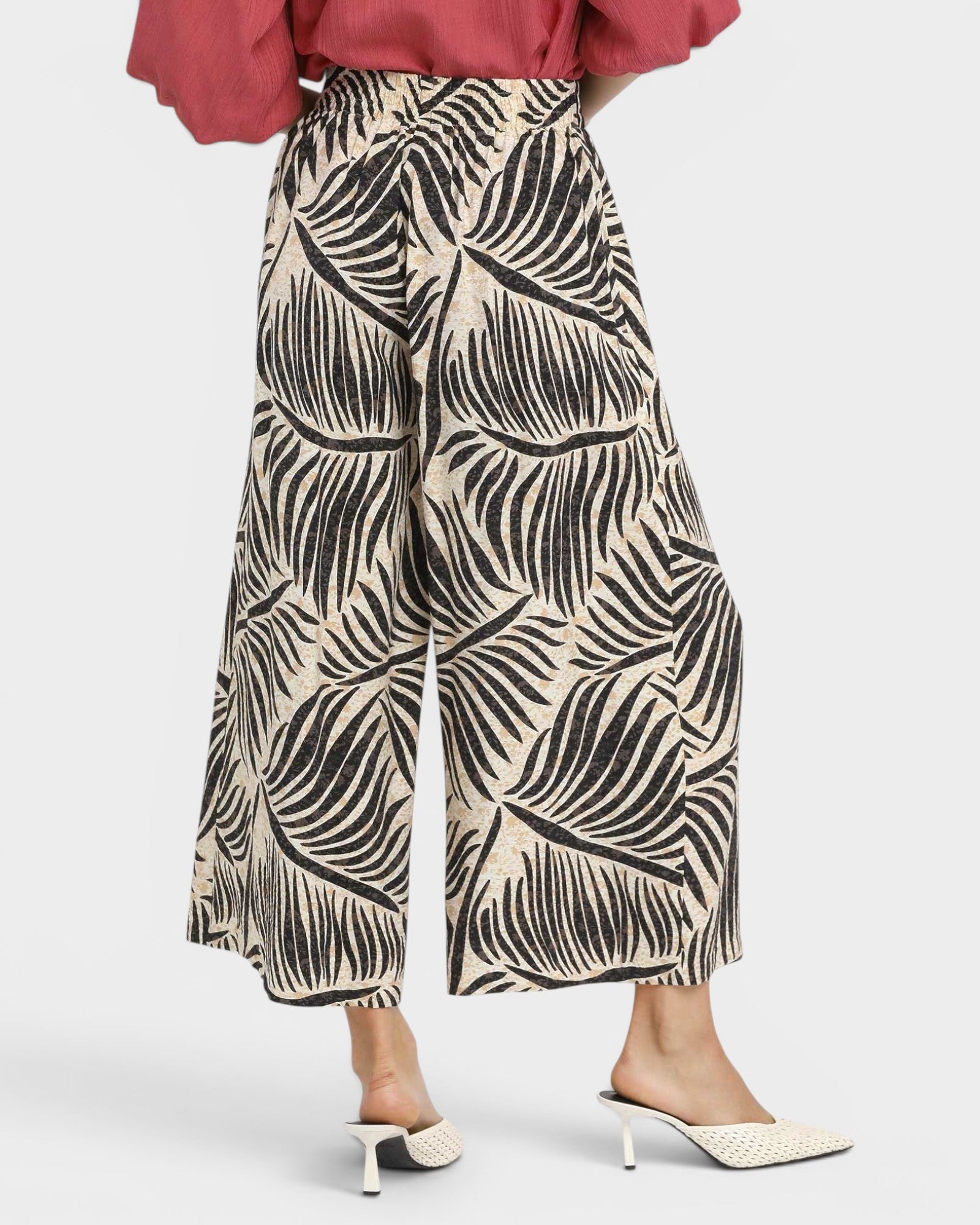 Person wearing wide-leg pants with leaf pattern on a white background
