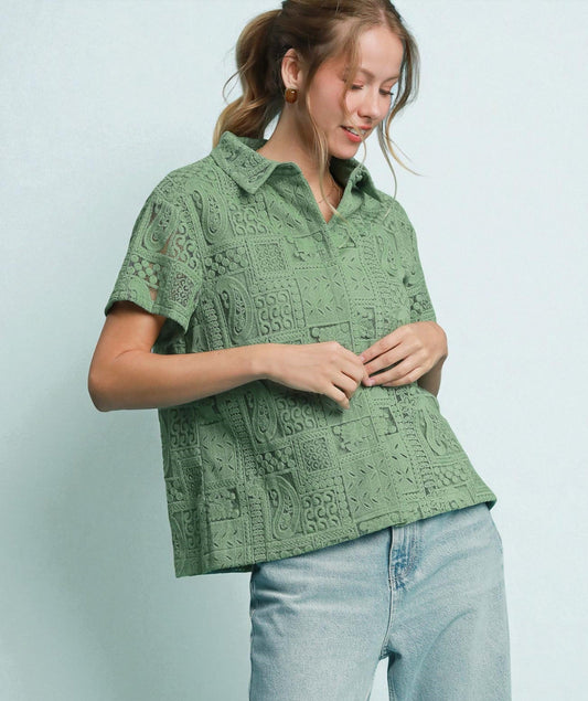 Woman wearing a green patterned shirt and light blue jeans against a light blue background