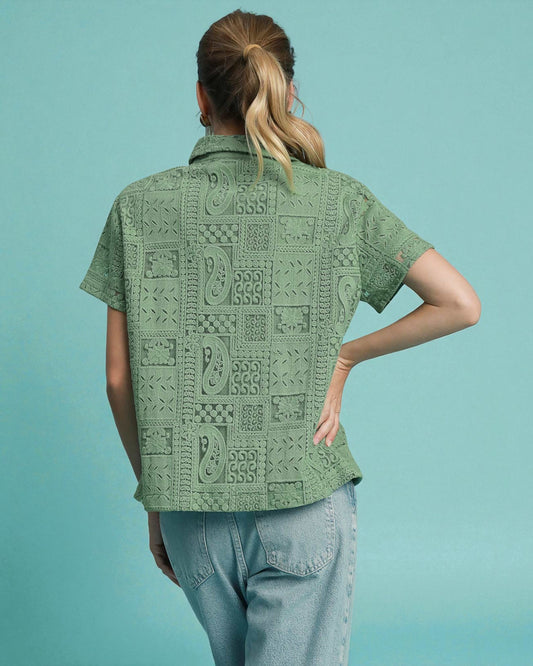 Person wearing a green patterned shirt against a light blue background