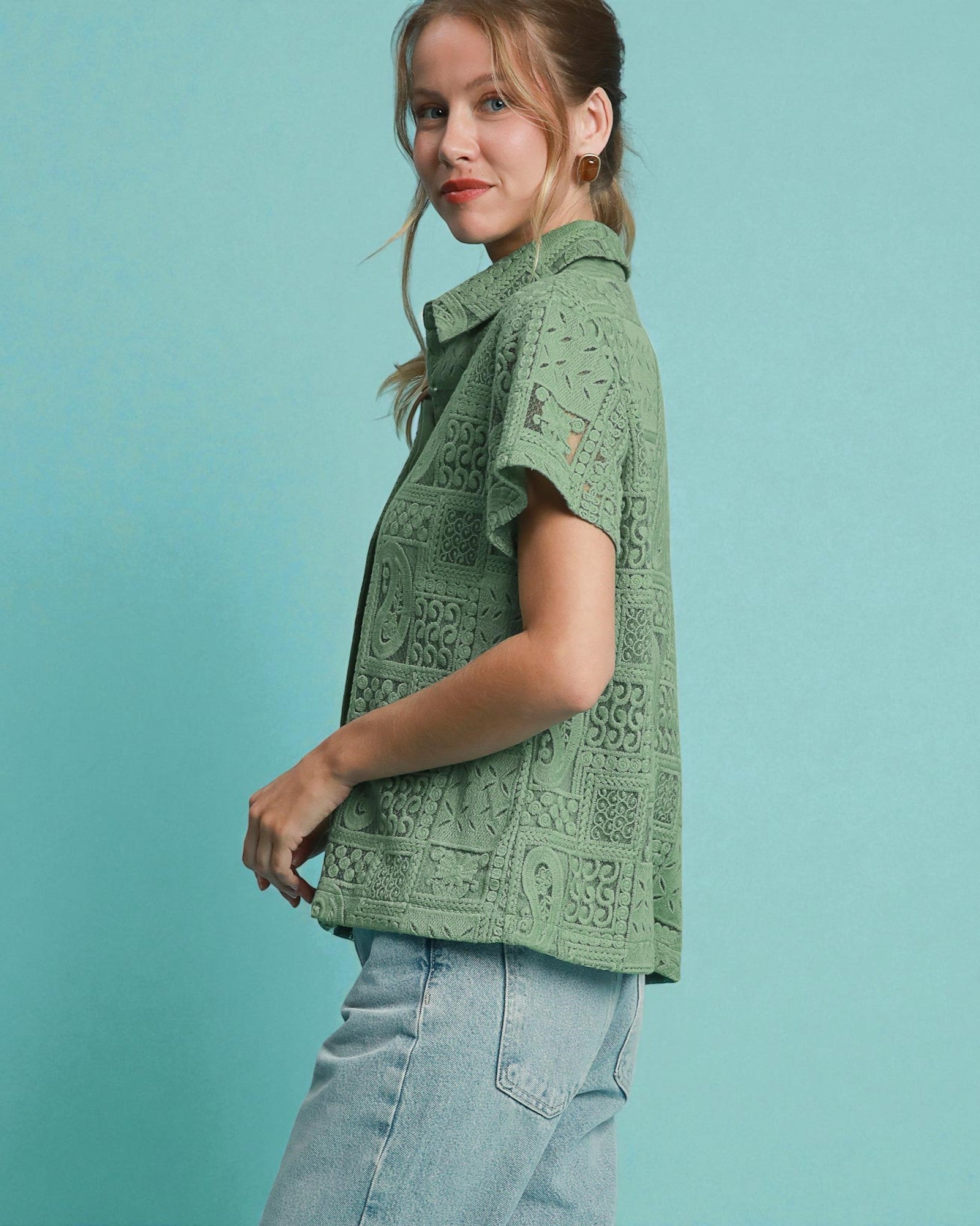 Woman wearing a green patterned top against a teal background