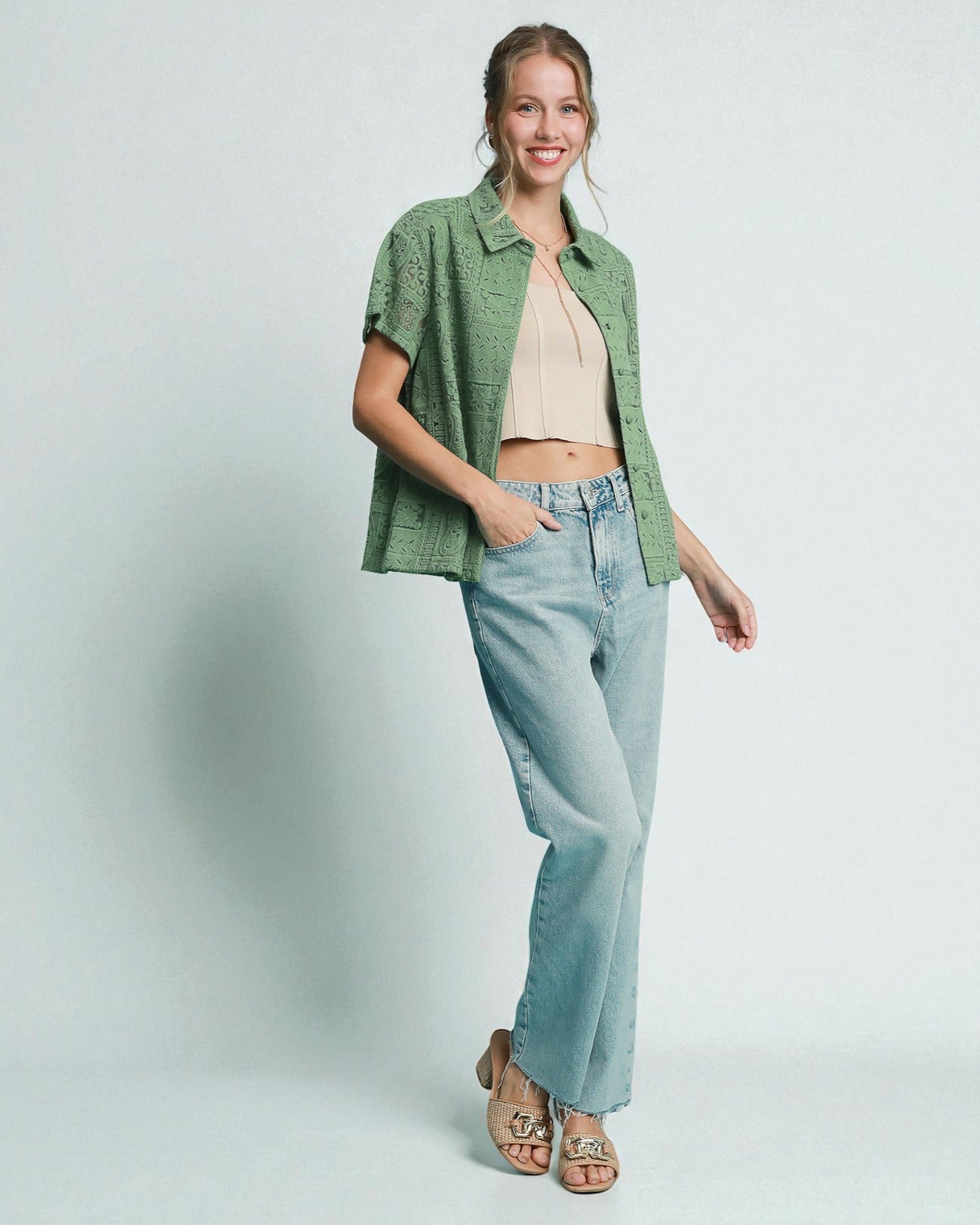 Woman wearing a green checkered shirt, beige top, and light blue jeans on a white background