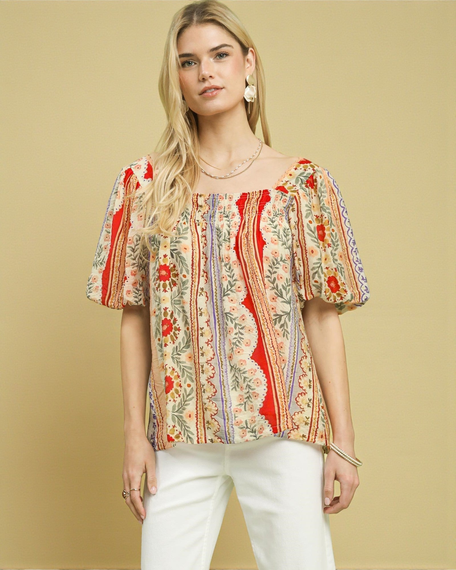 Woman wearing a colorful floral blouse against a beige background