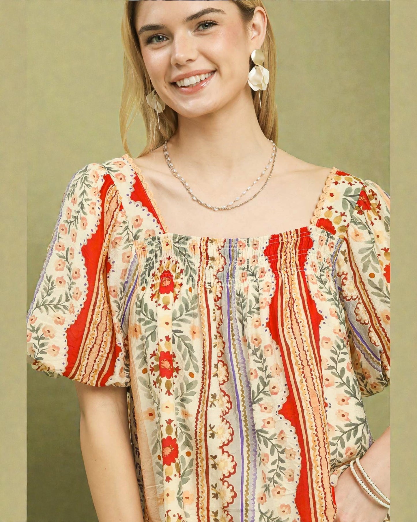 Woman wearing a colorful patterned blouse with a green background