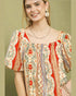 Woman wearing a colorful patterned blouse with a green background