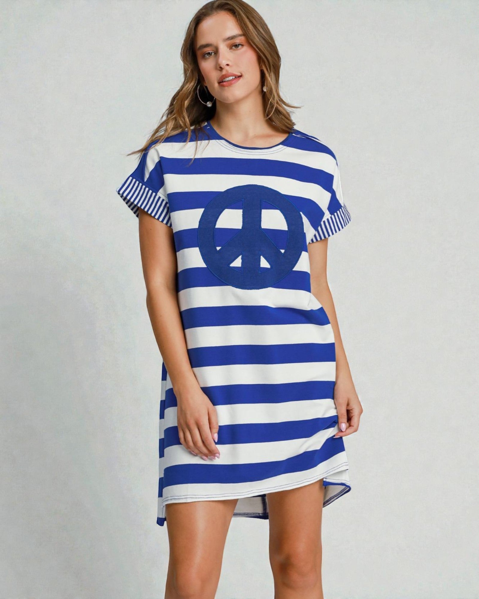 Woman wearing a blue and white striped dress with a peace symbol on a gray background