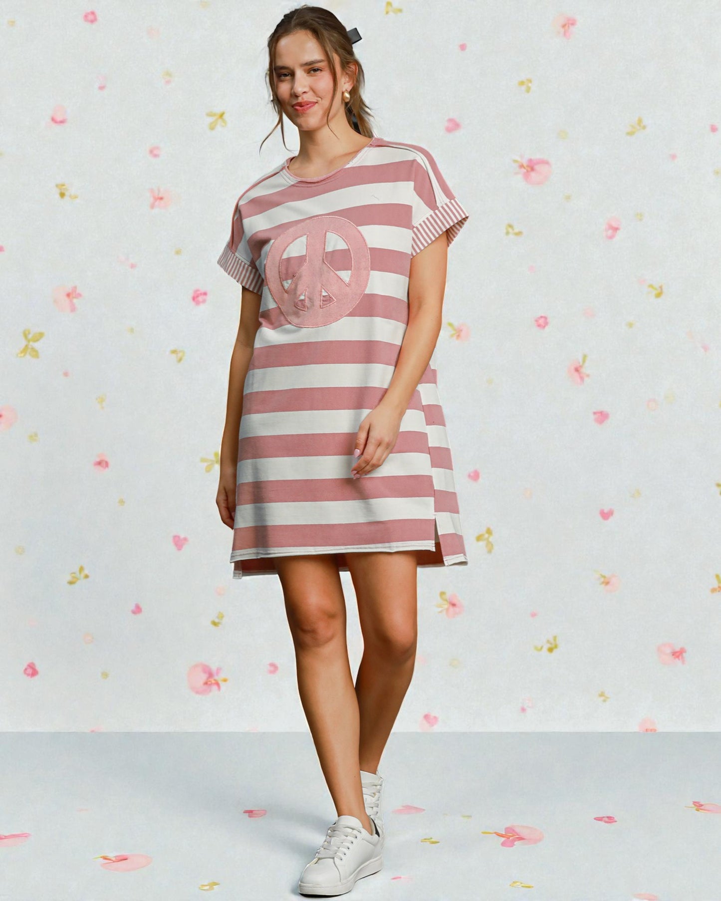 Woman wearing a pink and white striped dress with a peace symbol on a light background
