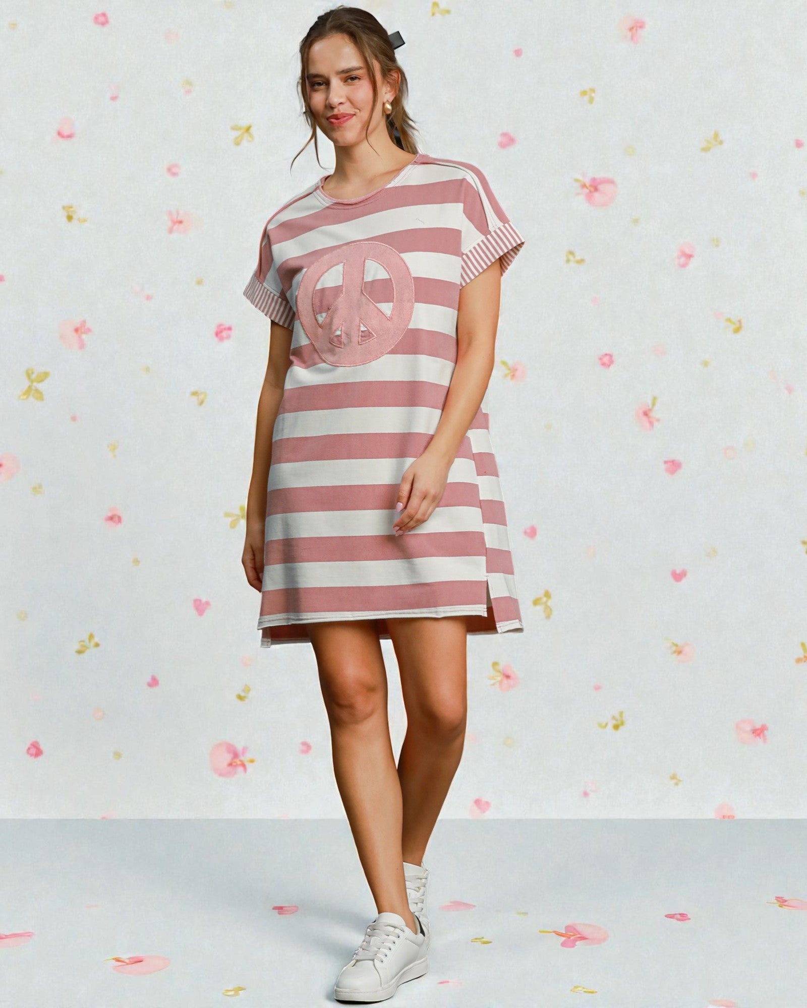 Woman wearing a pink and white striped dress with a peace symbol on a light background