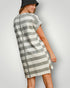 Woman wearing a gray and white striped dress on a plain background