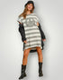 Person wearing a gray and white striped dress with a peace symbol, black jacket, and boots on a plain background