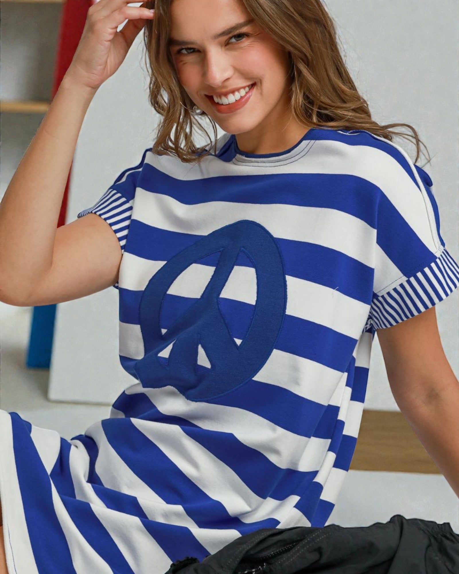 Woman wearing a blue and white striped dress with a peace symbol.