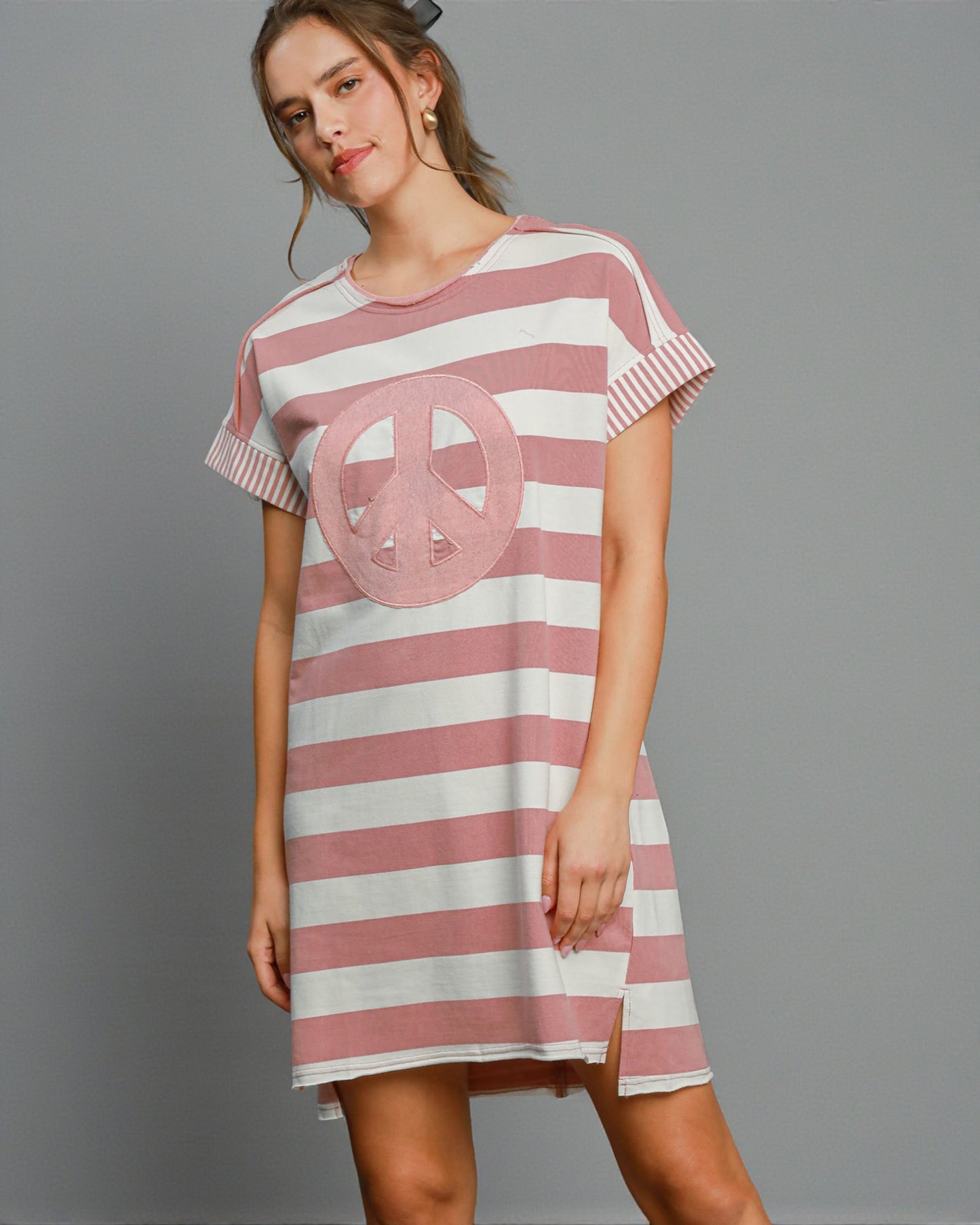 Woman wearing a pink and white striped dress with a peace symbol on a gray background