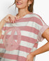 A close-up of a woman wearing a pink and white striped t-shirt with a large pink peace sign applique on the front.
