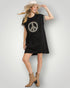 Woman wearing a black dress with a peace symbol design, tan boots, and a white hat on a light gray background.
