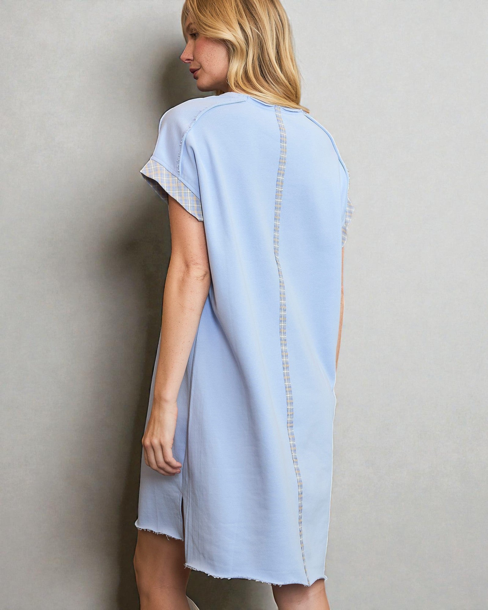 Woman wearing a light blue dress with lace trim against a plain background