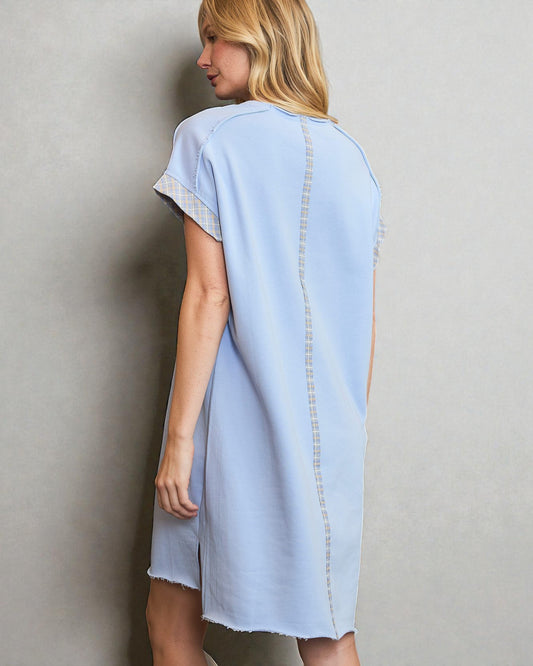 Woman wearing a light blue dress with lace trim against a plain background