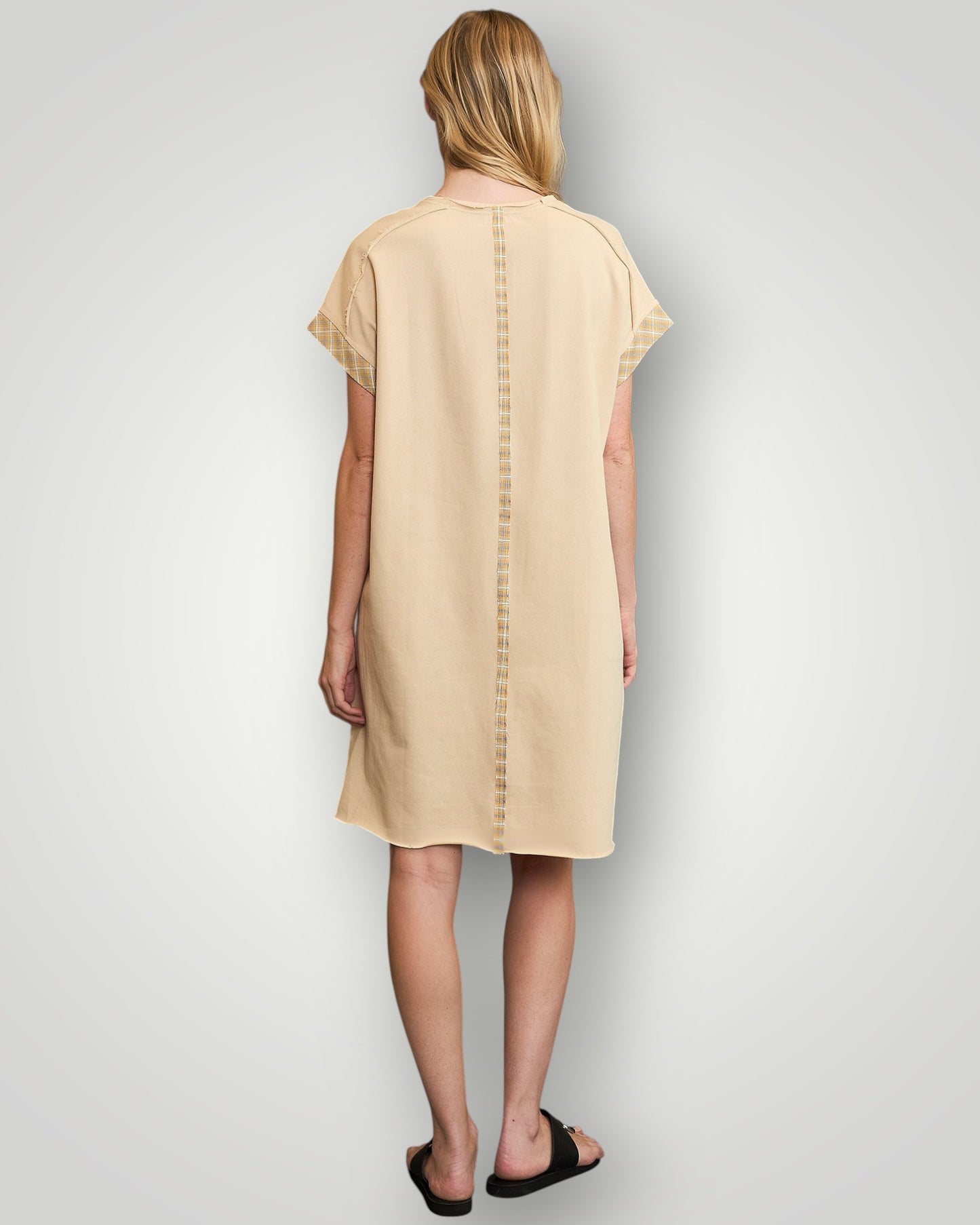 Woman wearing a beige dress with a plain background