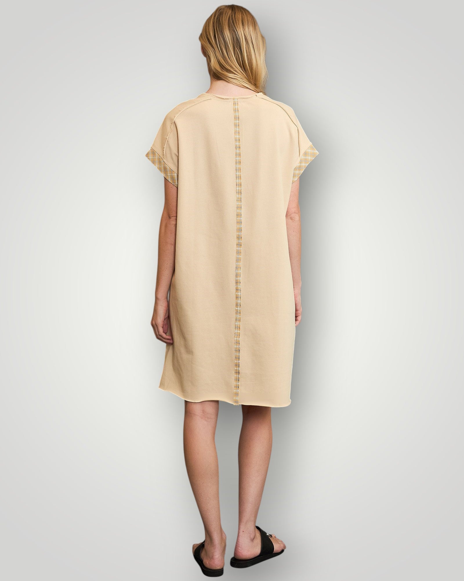 Woman wearing a beige dress with a plain background