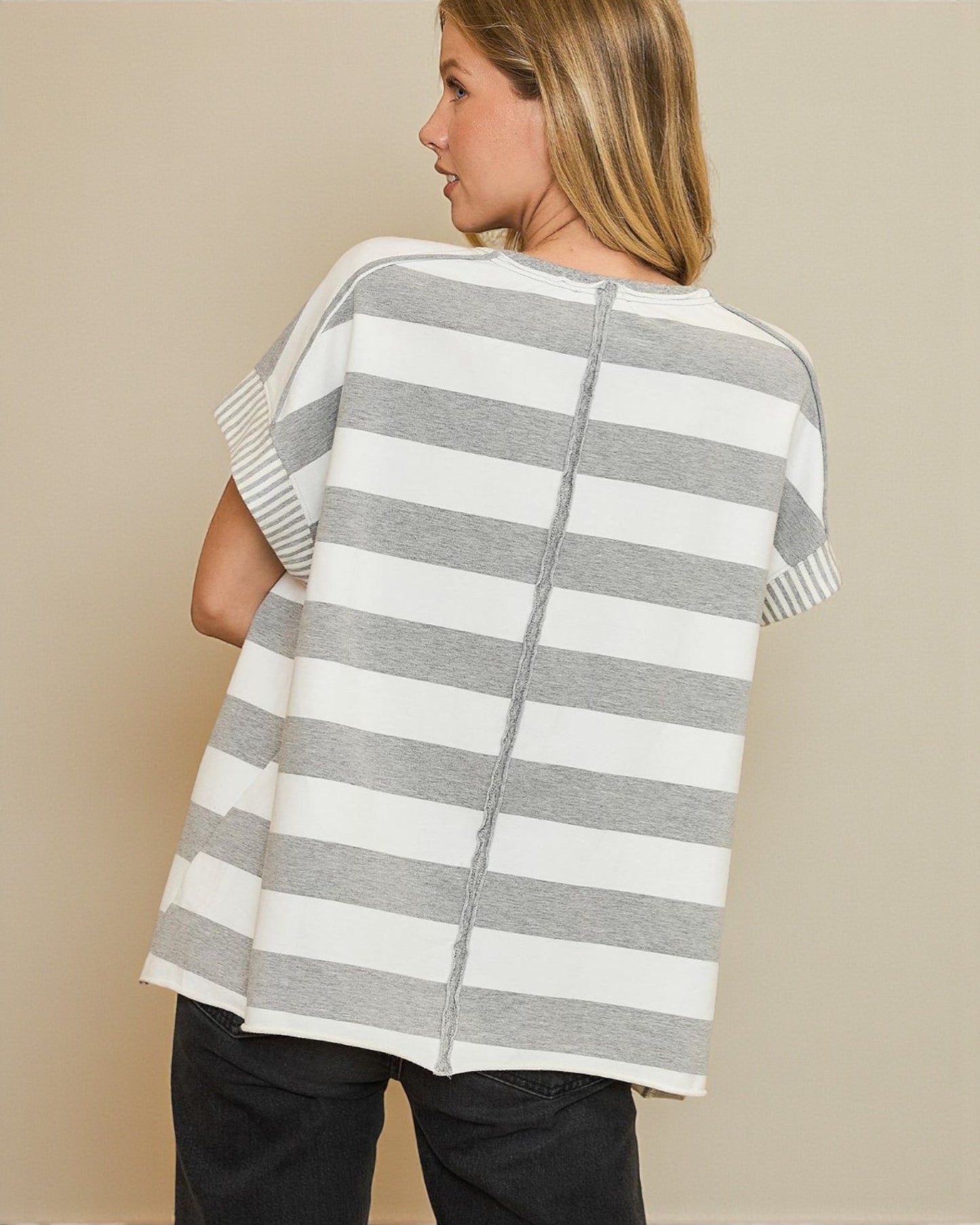 Woman wearing a gray and white striped sweater against a beige background